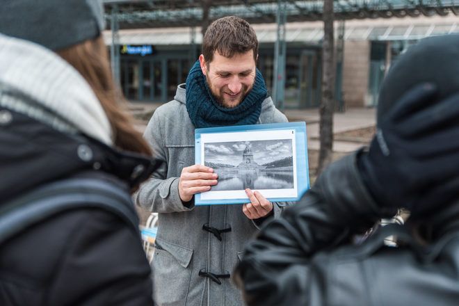 Guide showing a picture to travelers during a free walking tour with GuruWalk in Leipzig, Germany.