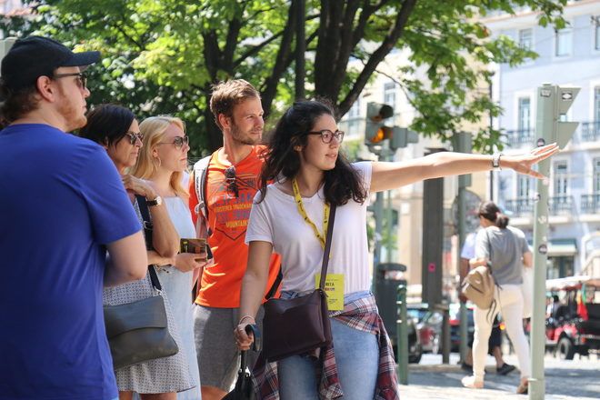 Tour guide showing something to travelers during a free walking tour in Lisbon with GuruWalk.